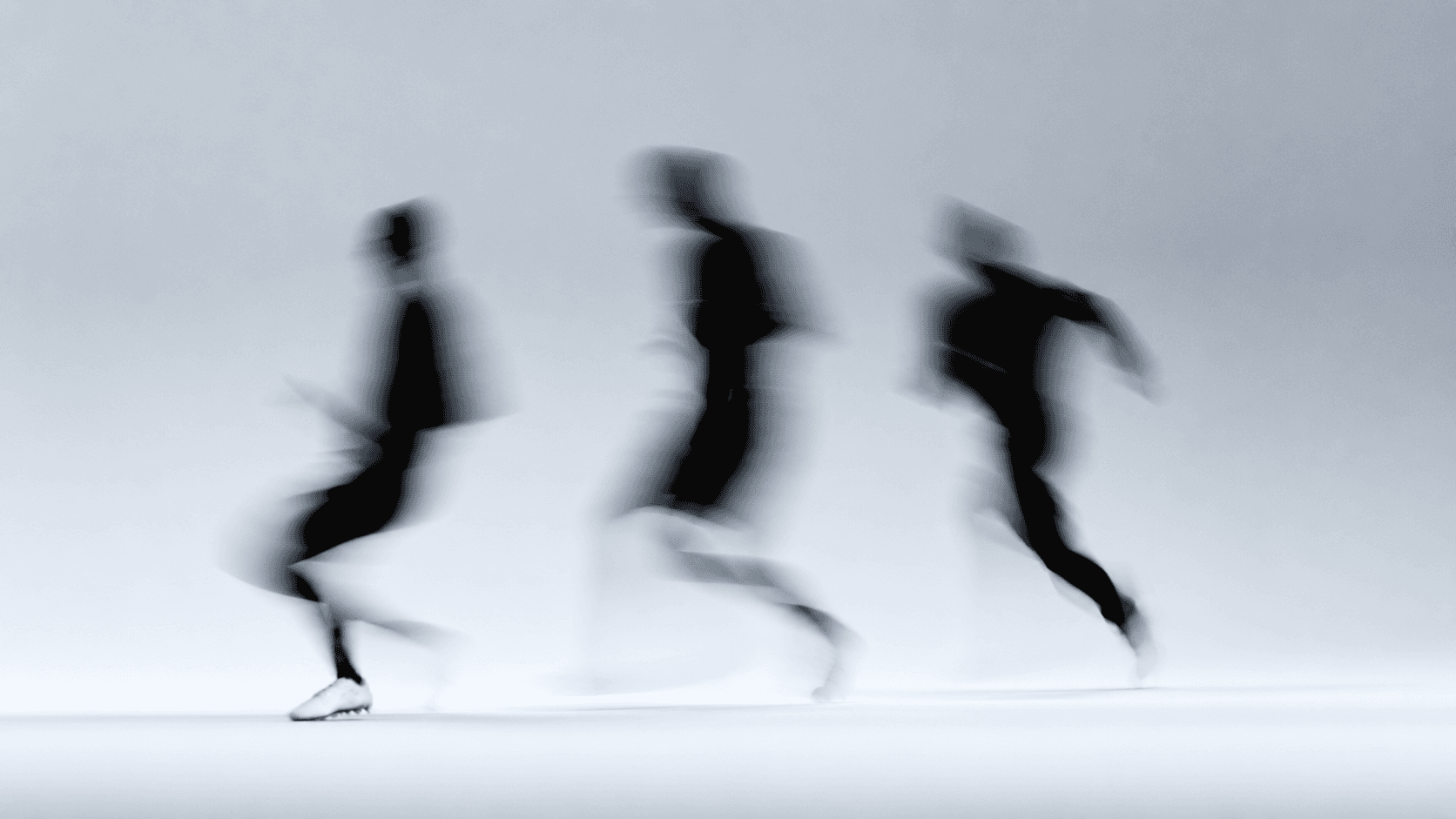 Tres personas corriendo, capturadas con motion blur sobre fondo claro
