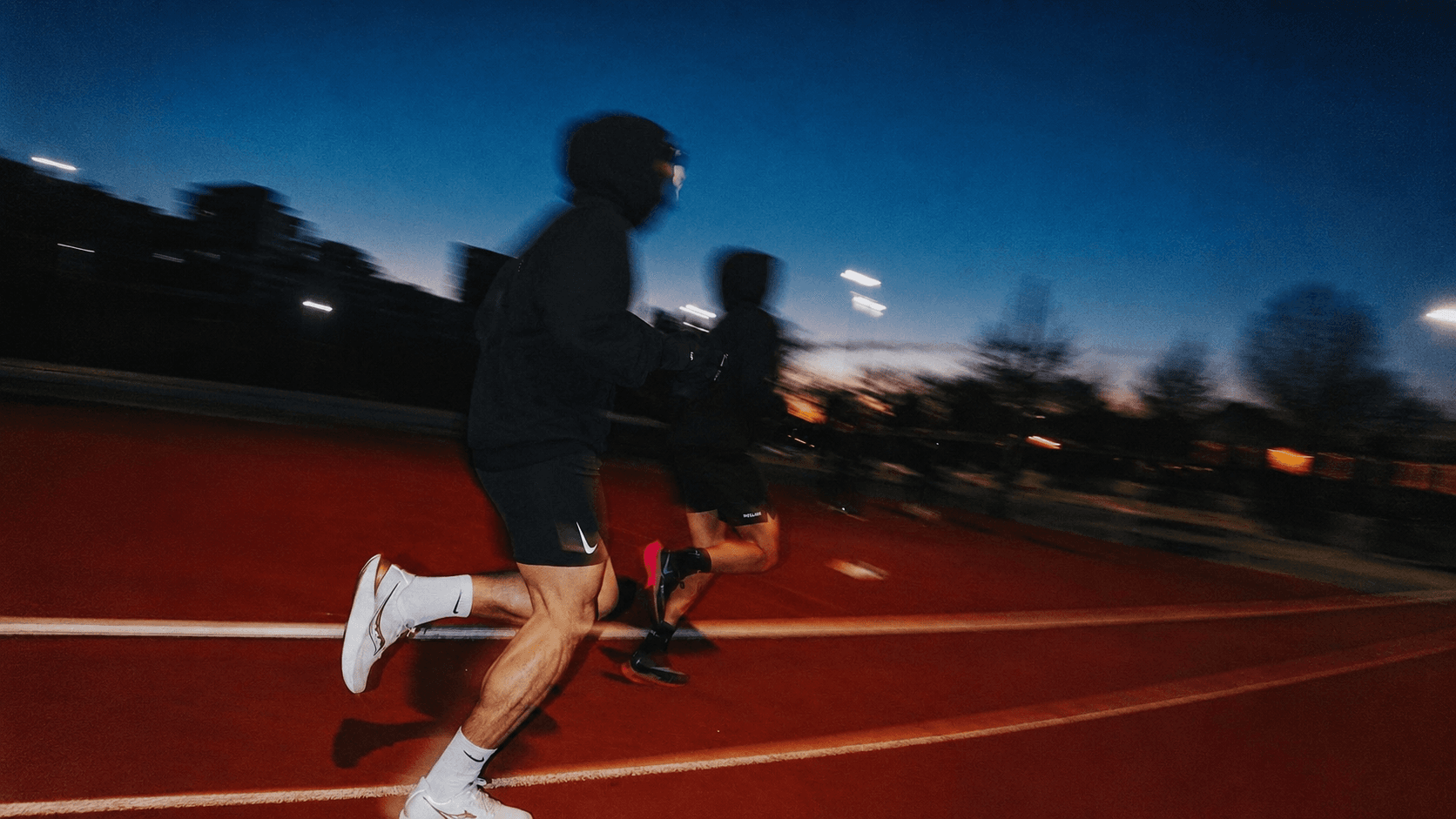 Dos personas corriendo al amanecer en una pista de atletismo